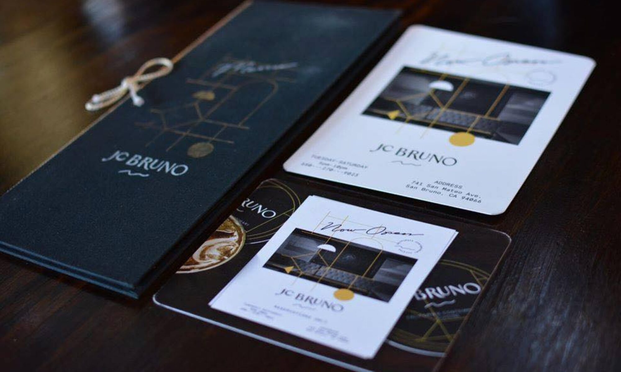 JC Bruno Restaurant menus and cards on a dark wood table