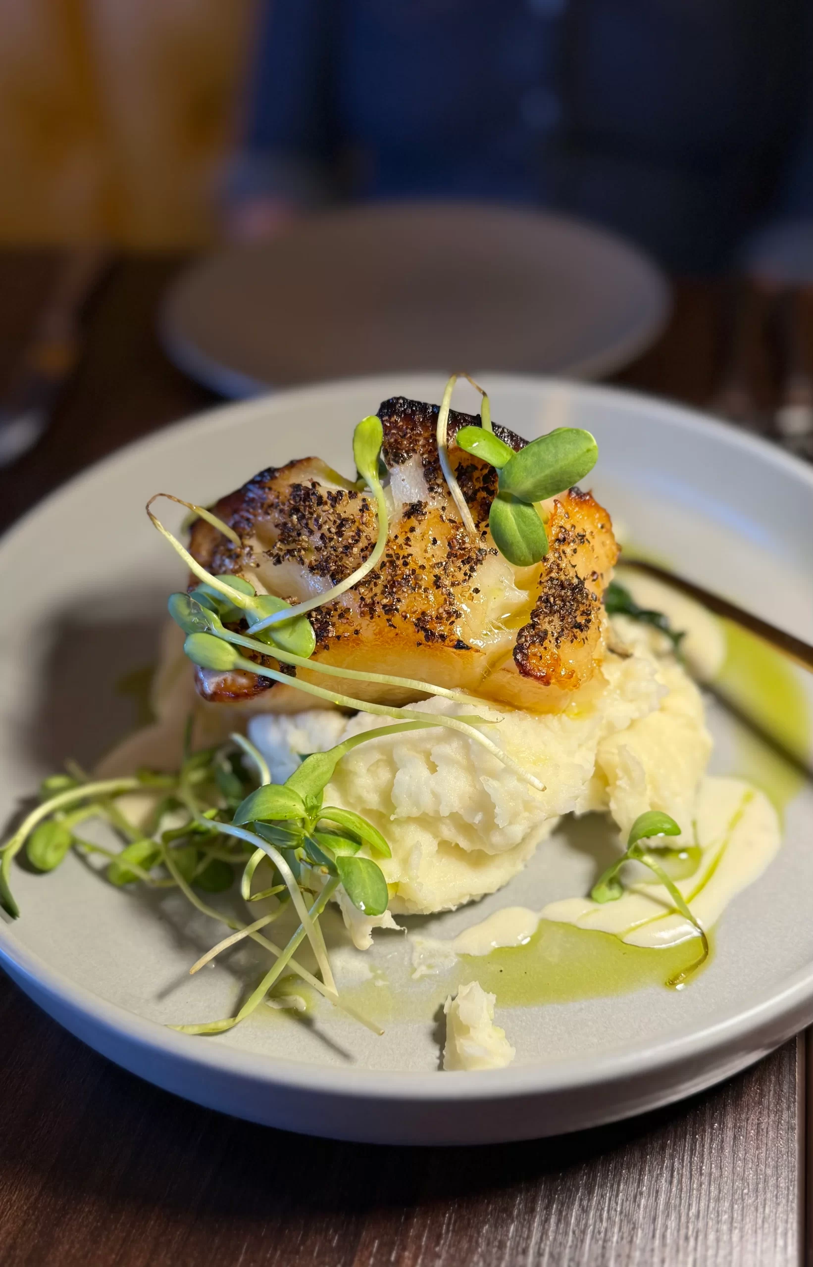 Pan-Seared Fish with Whipped Potatoes Pan-seared fish fillet over whipped potatoes with pea shoots and herb oil